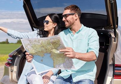 2 people holding map in boot of car