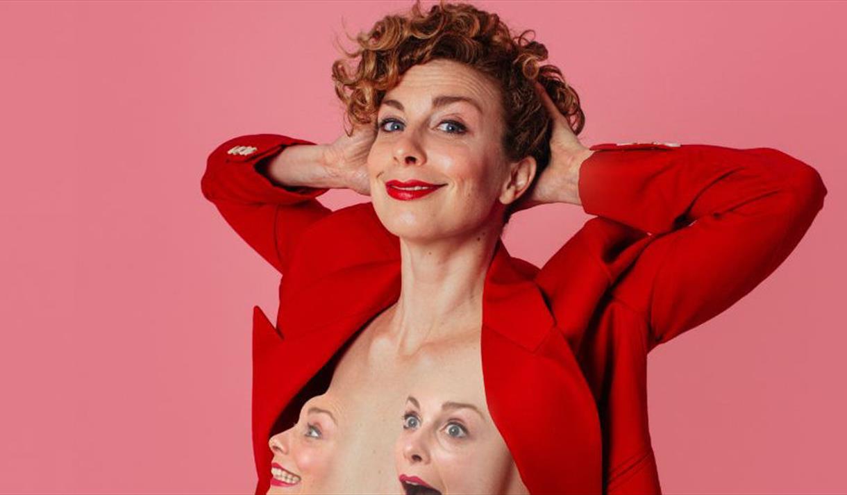 Helen Duff wearing a red blazer stood in front of a pink background
