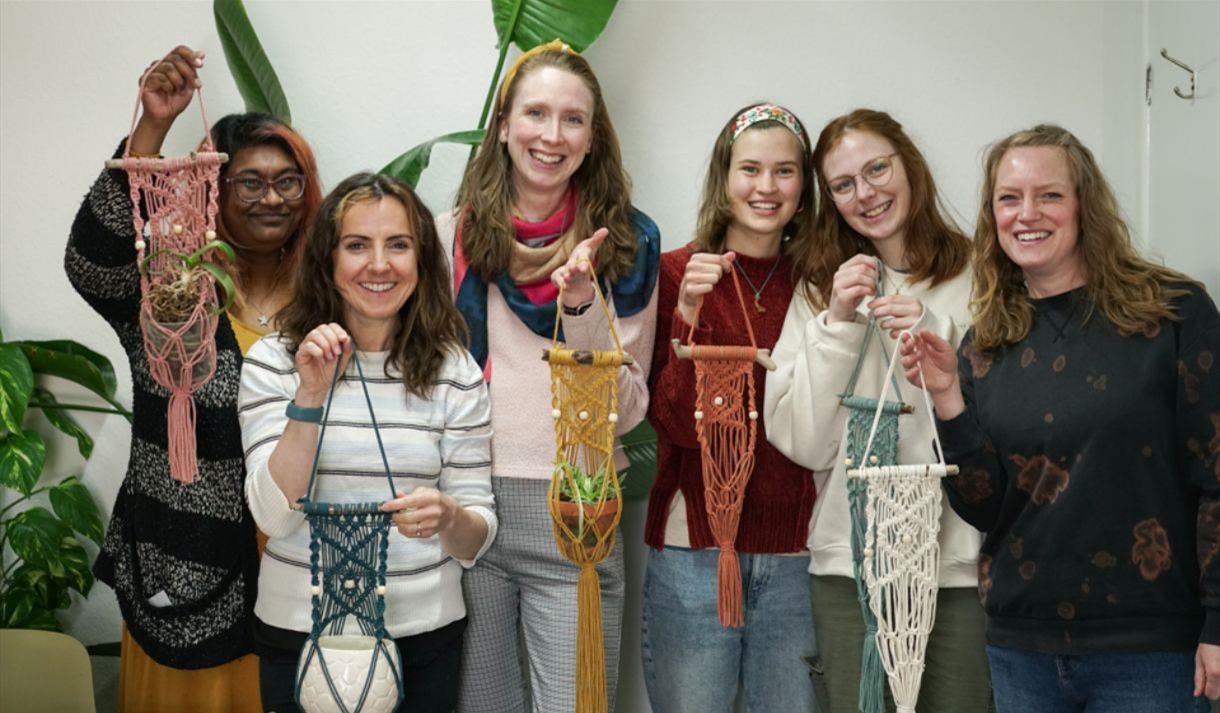 A group of women holding macrame plant hangers