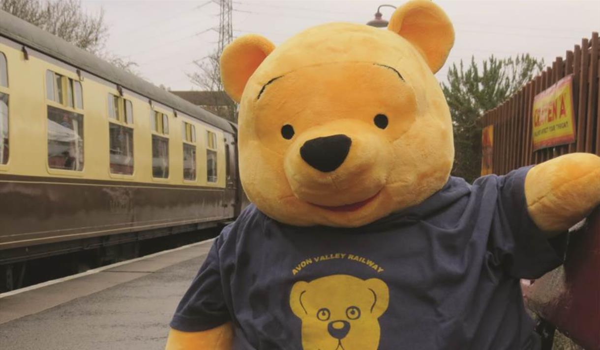 A giant yellow teddy bear on a train platform