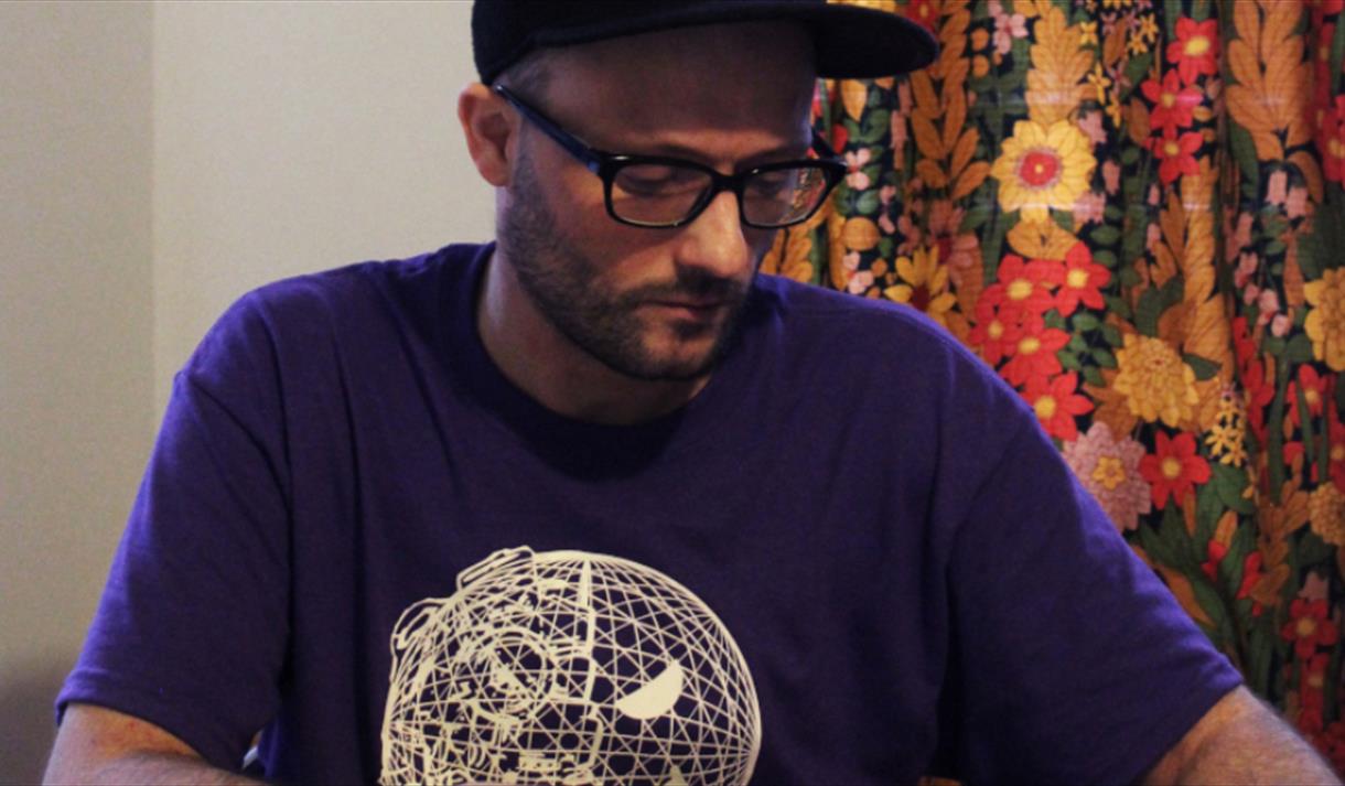 A man wearing a purple shirt with a white globe on the front