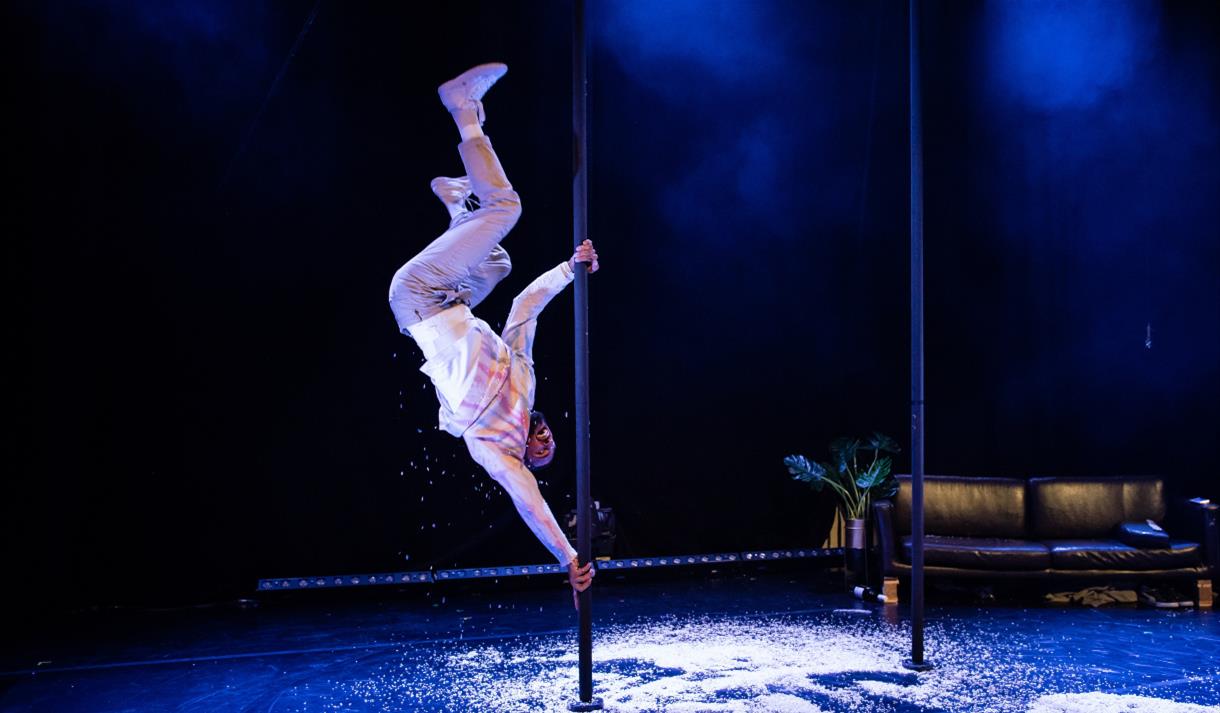 A man lifting himself up a pole upside down