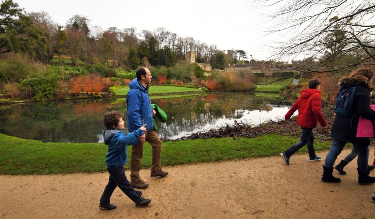Family on garden path by a large pool.