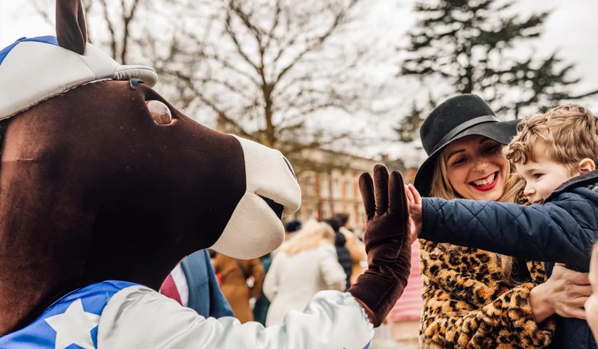 Scotty the Ascot mascot 'high fives' a young visitor