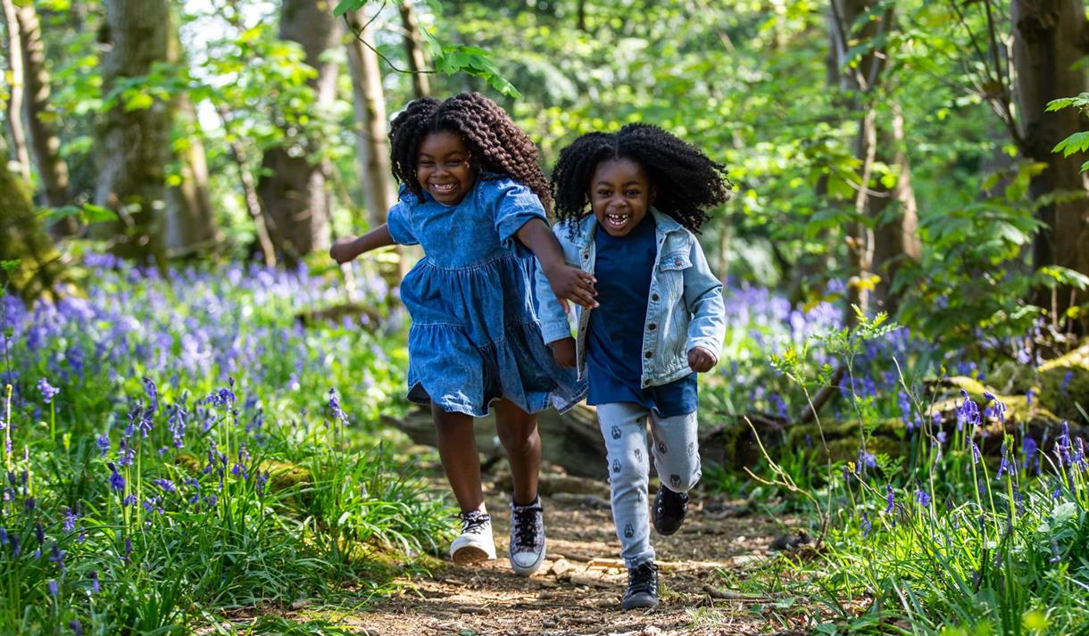 two girls running through spring woodland