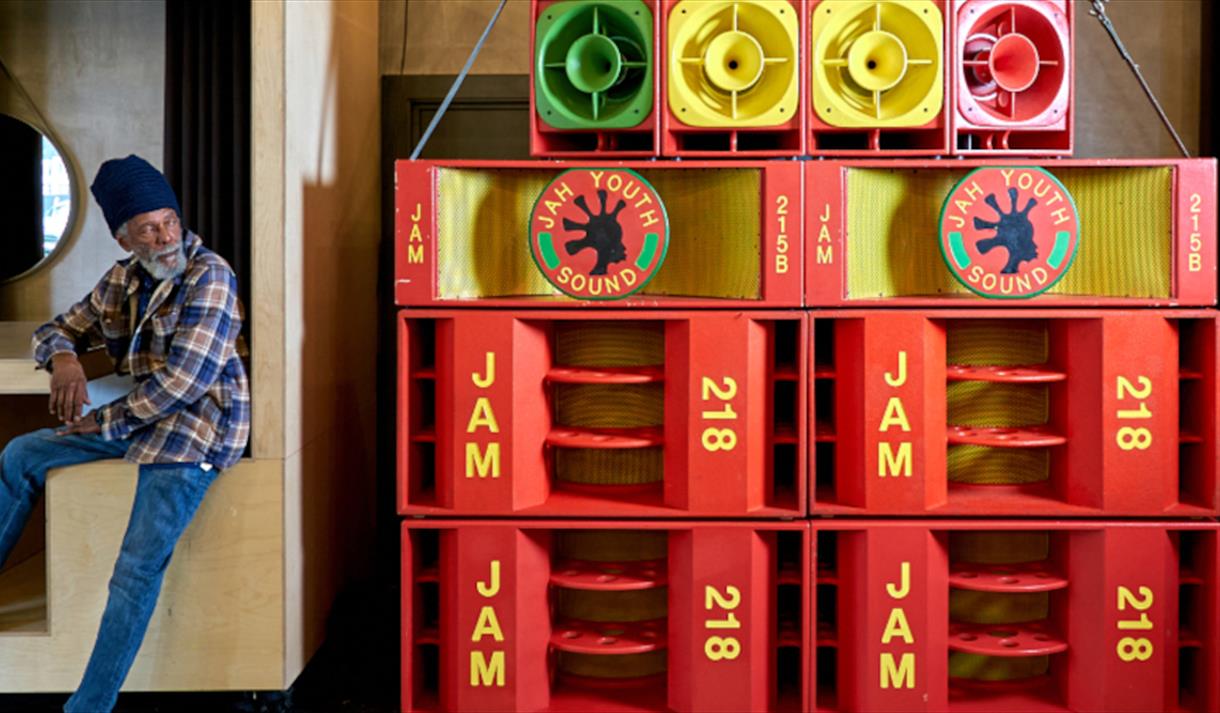 A man sat in front of a dislay that says ' Jam 218'