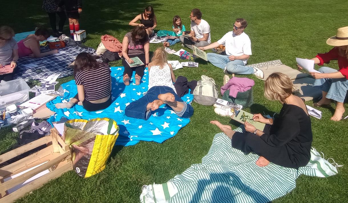 A group of people sitting on a field on picnic blankets