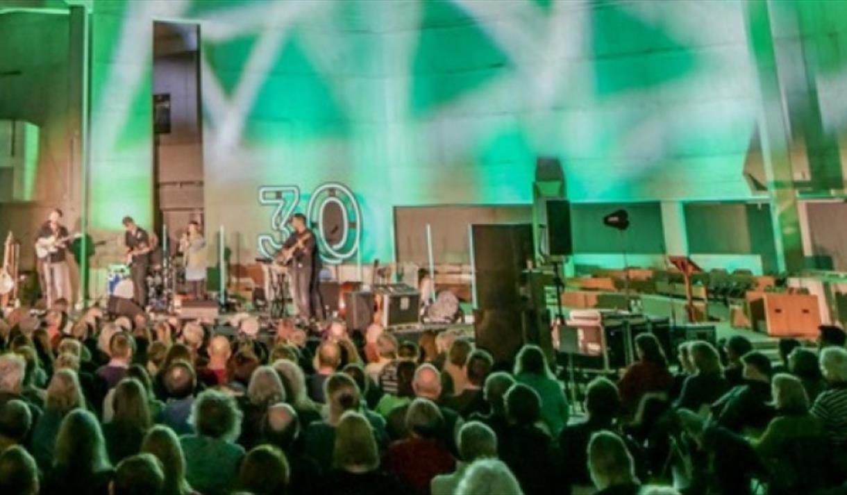 Person performing on stage in front of crowds with spotlights and green background light