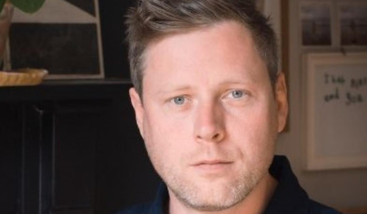 A headshot of a man looking directly at the camera