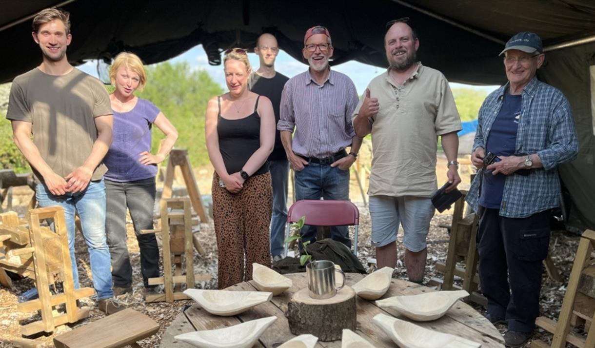 Group of people stood with their wooden carved bowls