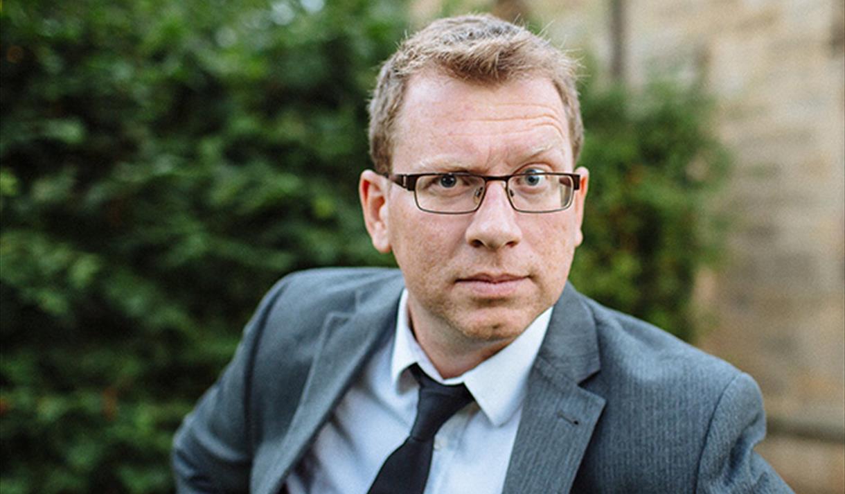 Man with glasses looking into camera with one eyebrow raised