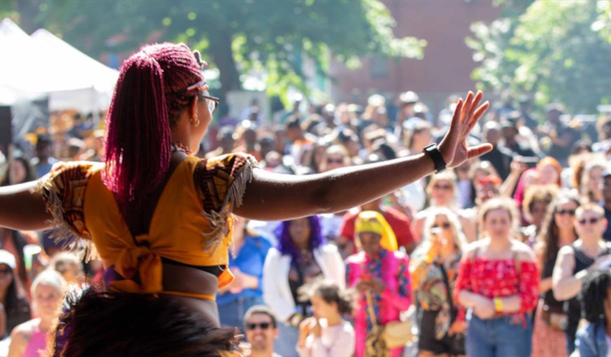 A women wearing a yellow top performing on a stage infront of a large crowd