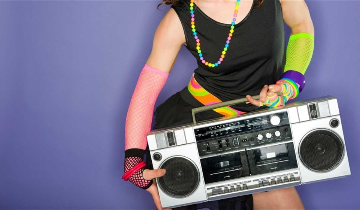 A women wearing bright colourful clothing holding a boom box