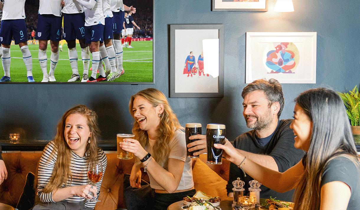 A group of people enjoying a pint watching the football