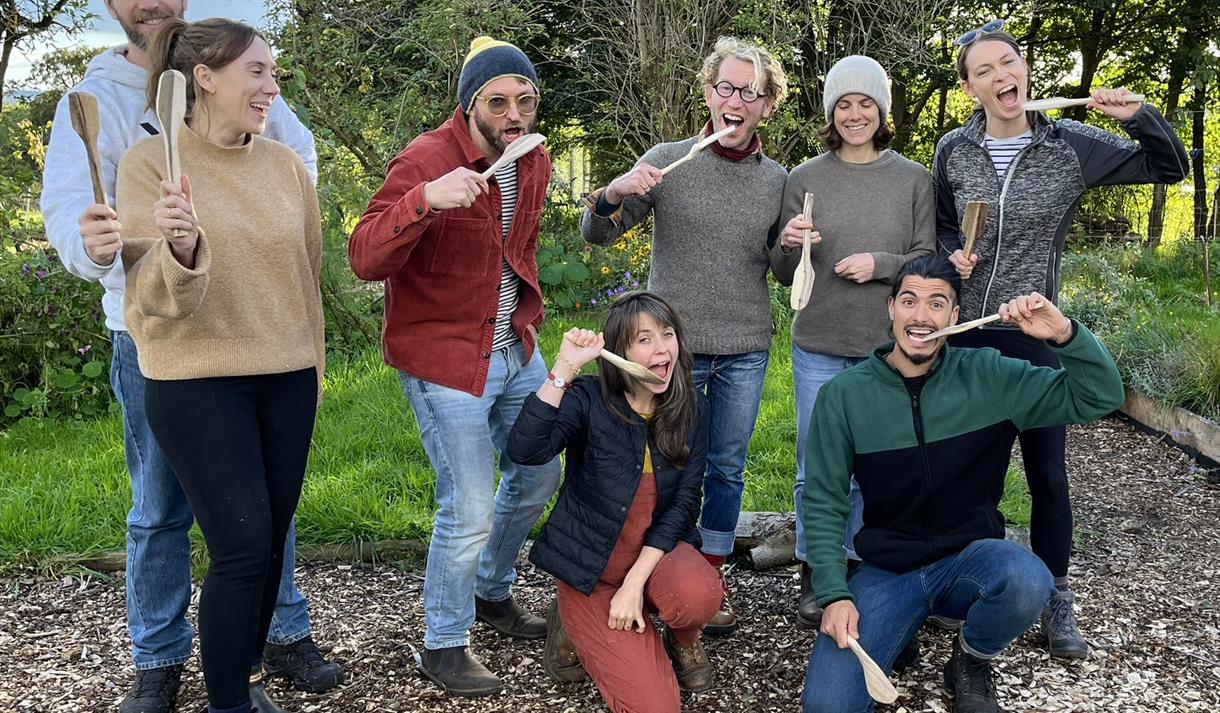 A group of people in woodland area with wooden spatulas
