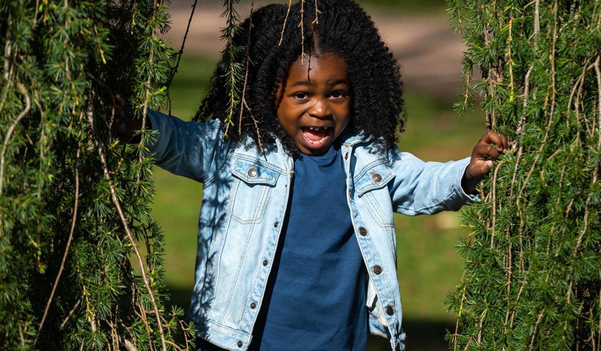 Young girl peeping through tree branches