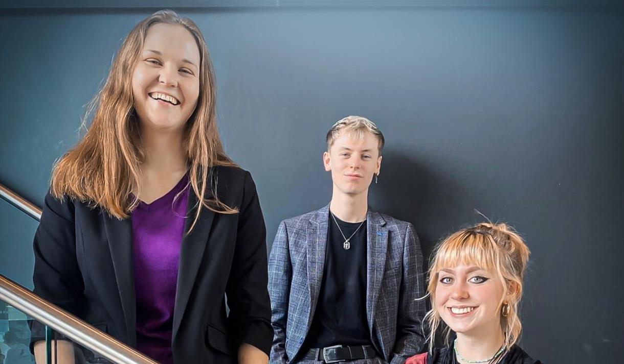 Three people smiling while standing on a staircase