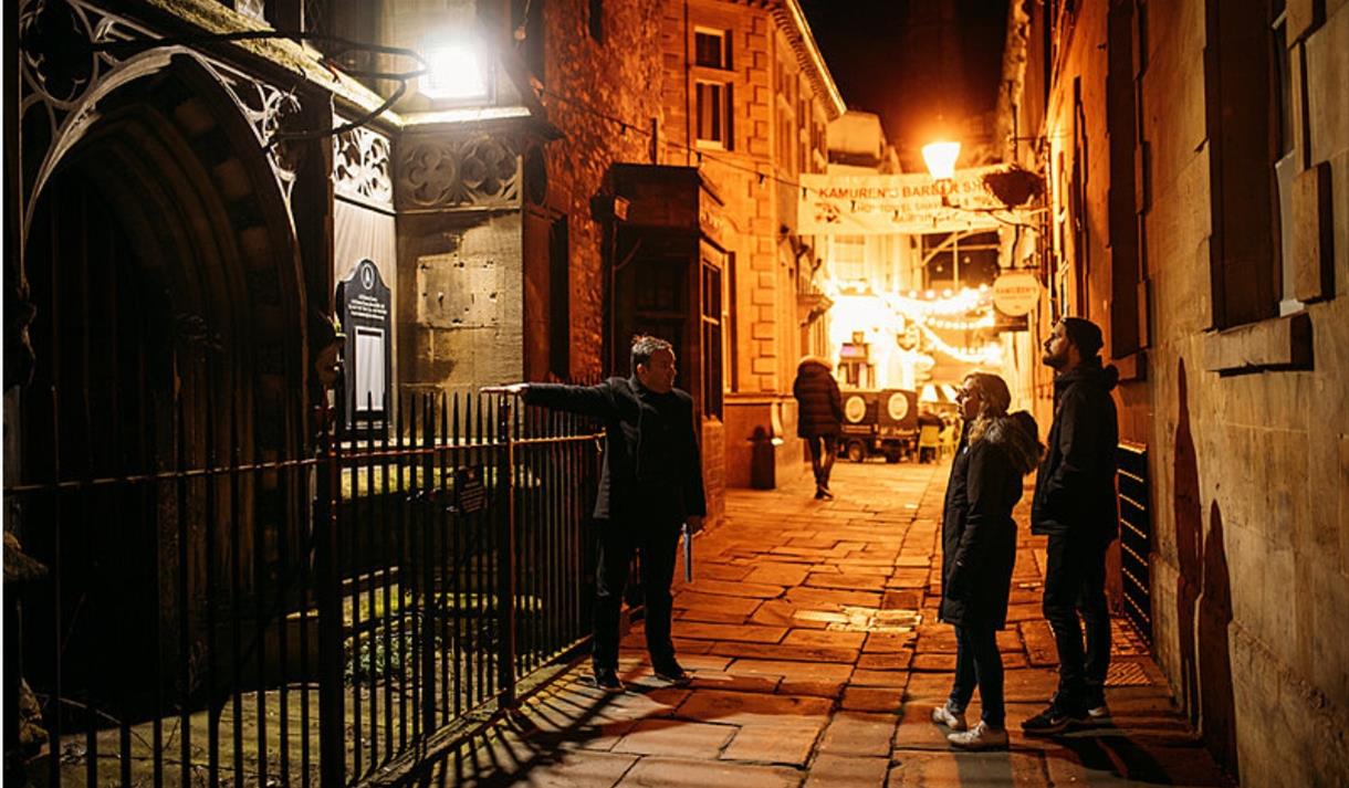 A tour guide pointing out a church to two participants
