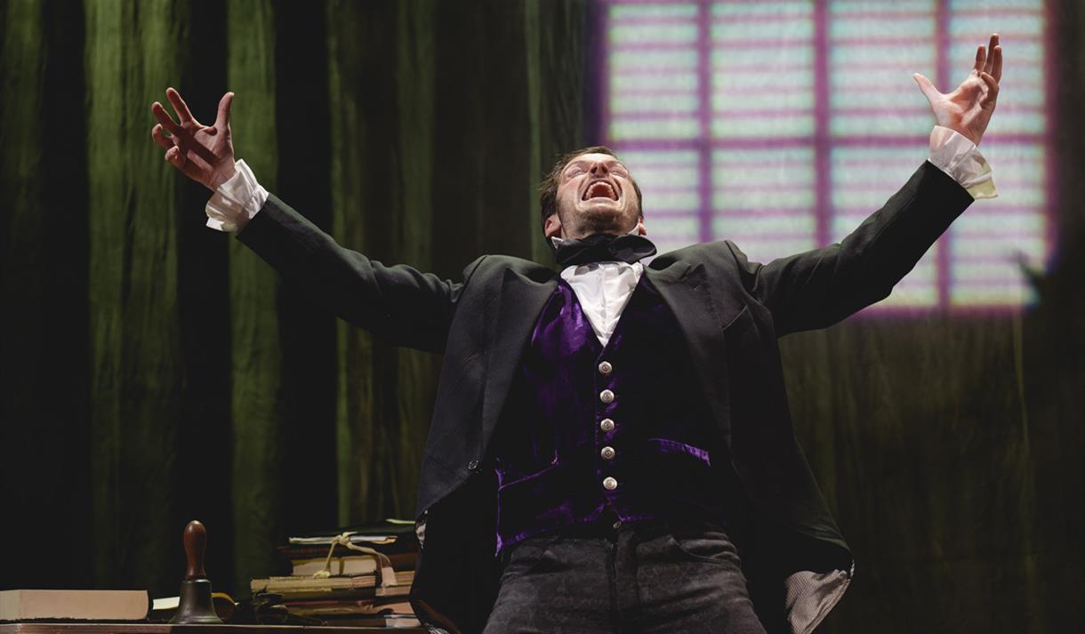 Man in victorian clothing raising his arms upwards and smiling