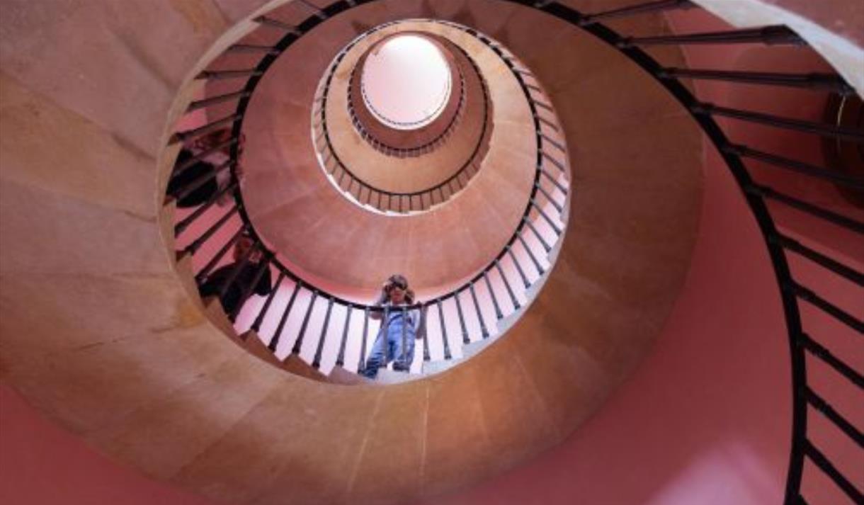 Photo of girl looking down at the camera from a spiral staircase