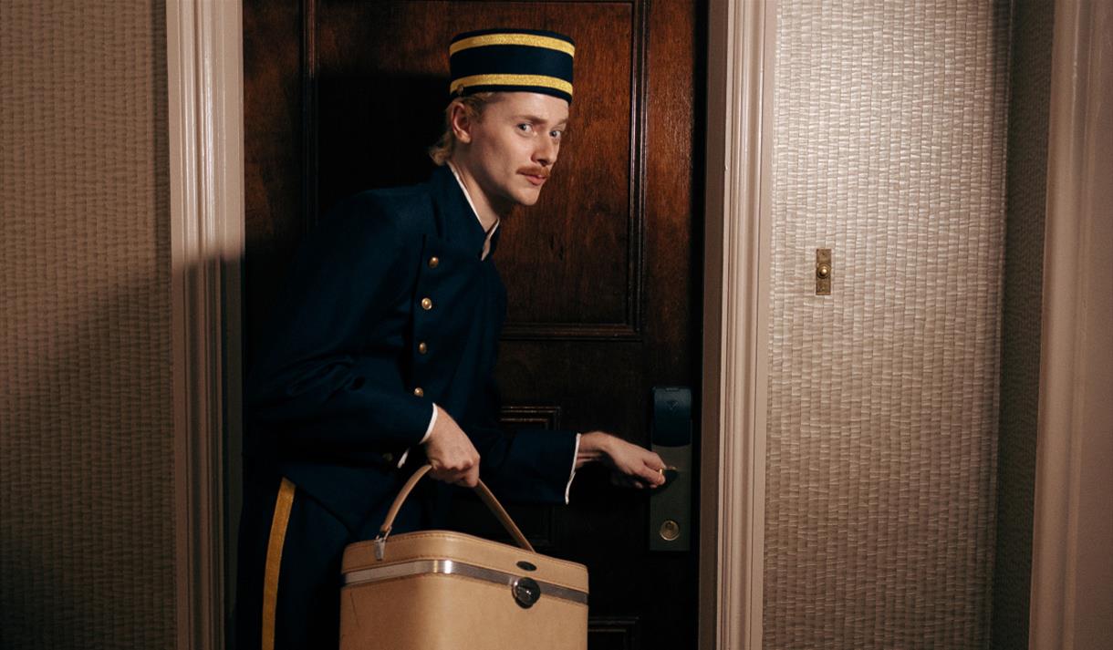 Bell boy opening a door in a hotel