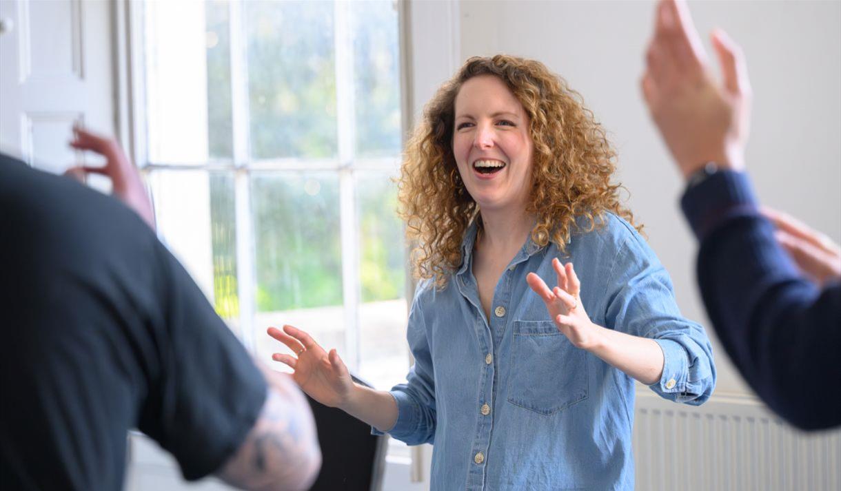 A women wearing a blue denim shirt taking part in an improv class