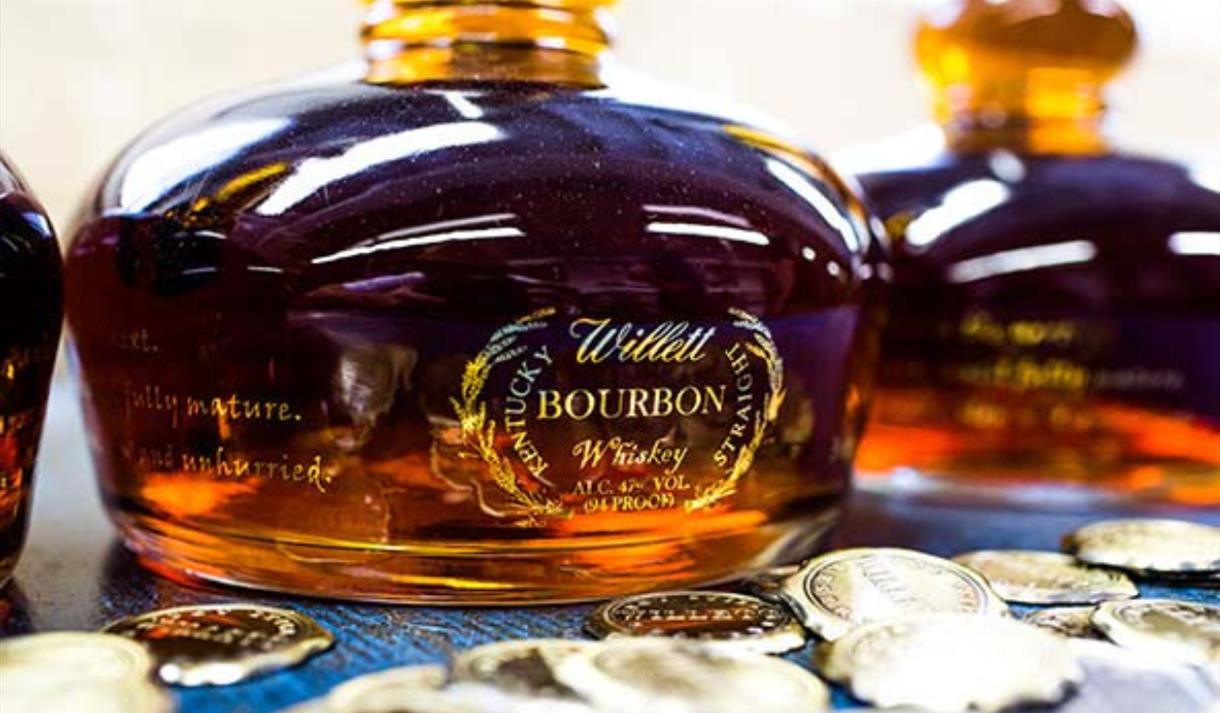 A close up picture of a willet bourbon bottle. The bottle is shaped like a pot still and full of bourbon.