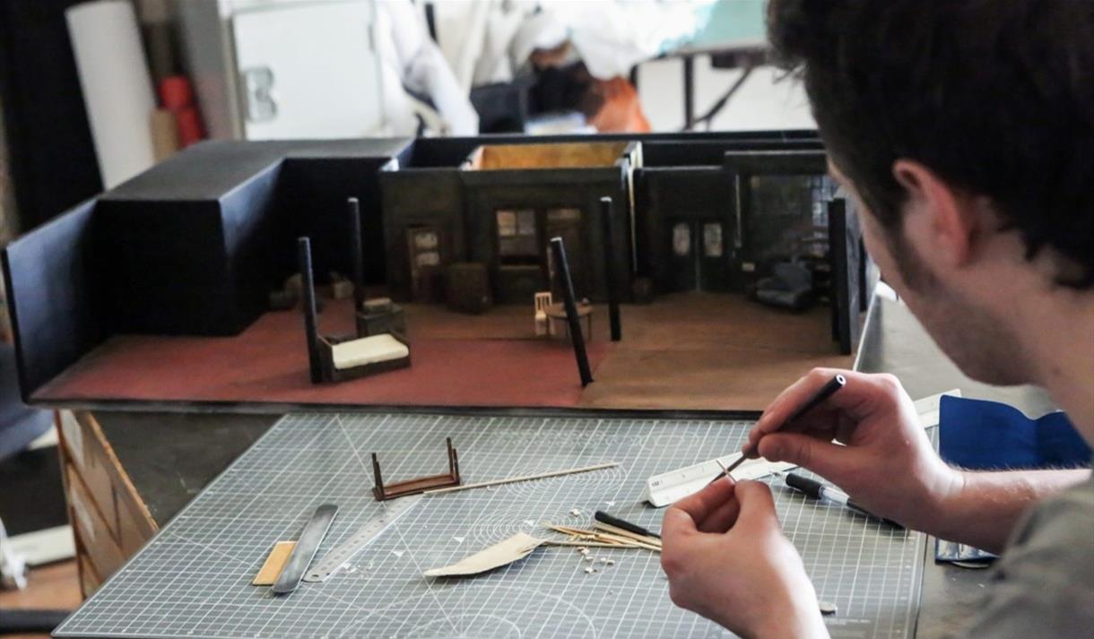 A man whittling wood at a table