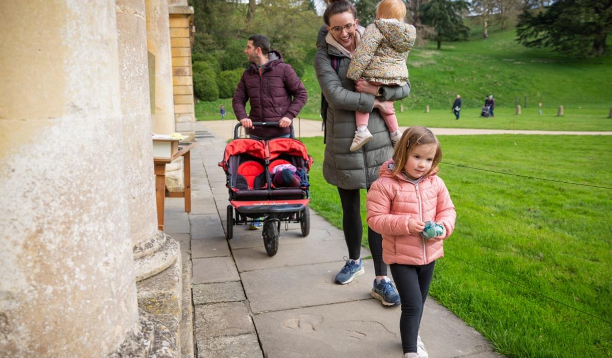 A family with a pushchair and Easter eggs outside the house at Dyrham Park