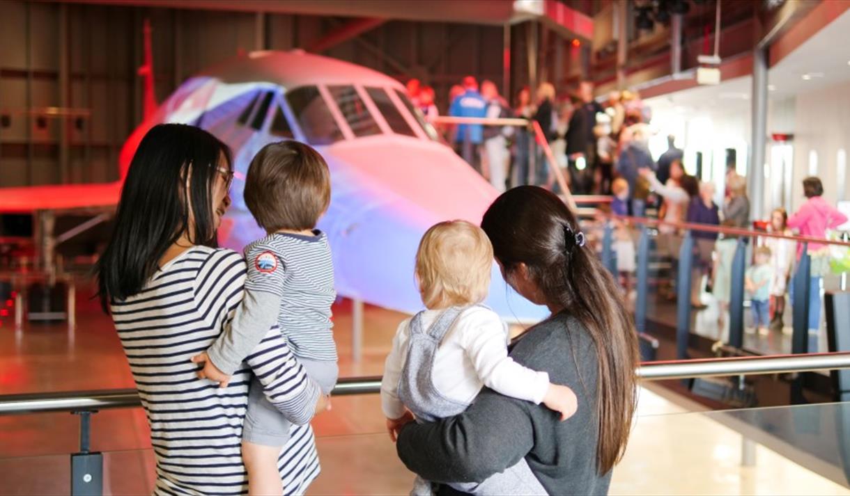 Women holding toddlers in front of Concorde