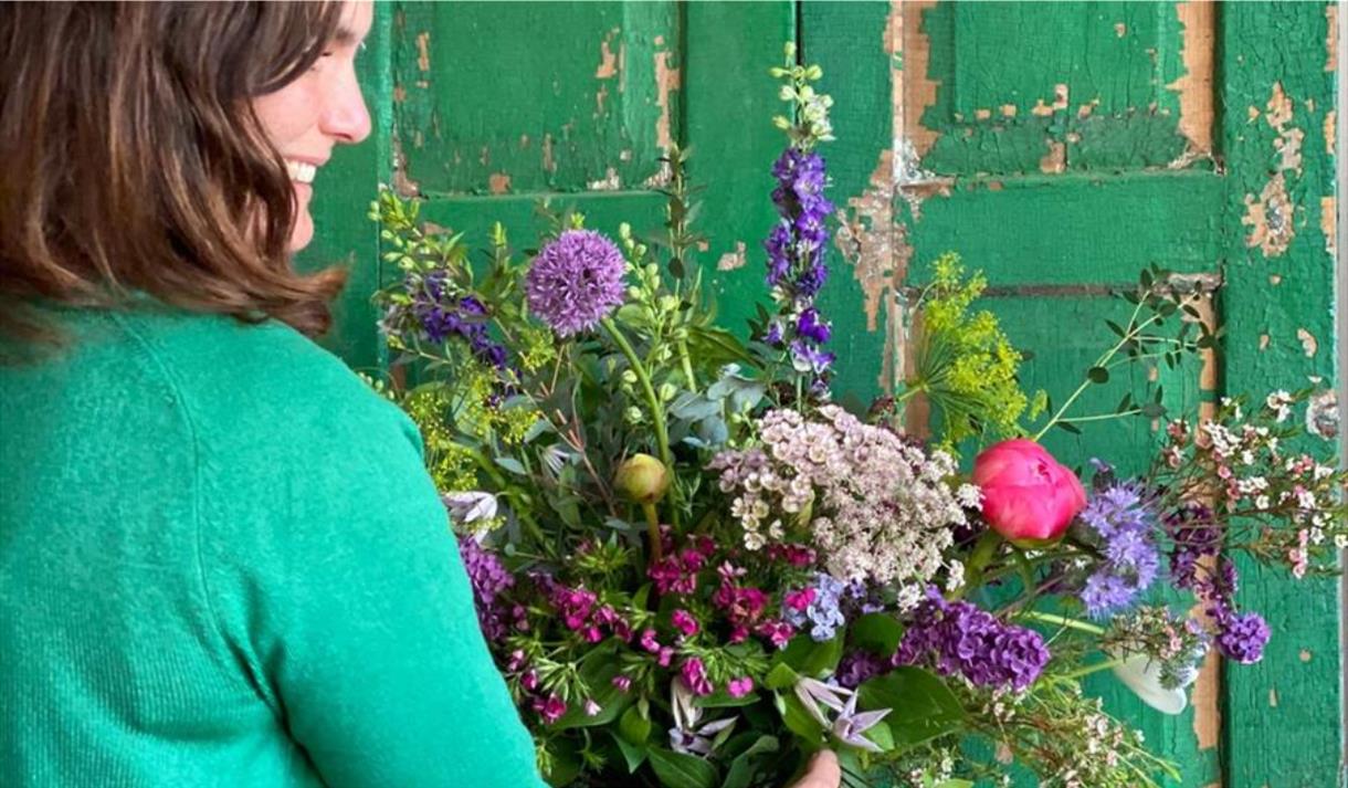A bouquet of brightly coloured flowers against a green door