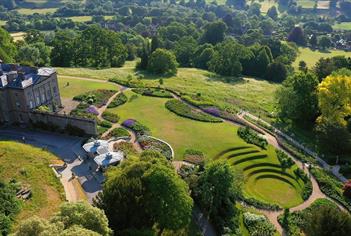 Manor house surrounded by green gardens overlooking valley