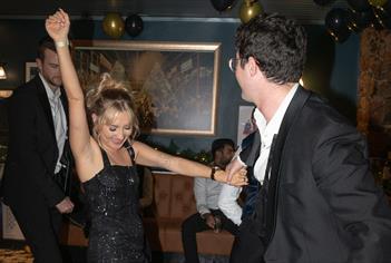 The image shows a lively and fun moment during a Racks Bar & Kitchen New Year's Eve celebration in Bristol. In the foreground, a young woman in a spar