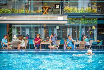 Bristol Lido - person swimming in pool and people dining by restaurant