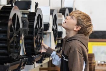 Boy looking at some large cogs on a machine at Saltford Brass Mill