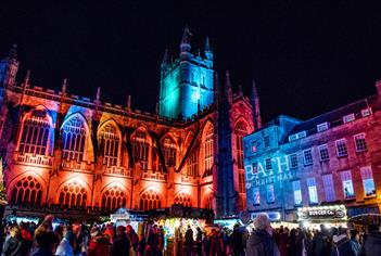 Bath Abbey lit in Christmas lights with market stalls in foreground
