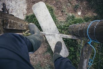 person wearing boots climbing over countryside stile