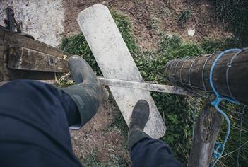 person wearing boots climbing over countryside stile