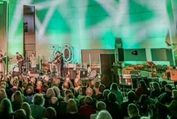Person performing on stage in front of crowds with spotlights and green background light