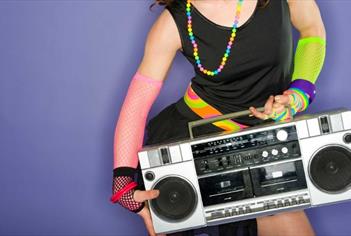A women wearing bright colourful clothing holding a boom box