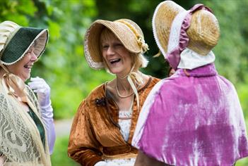 Three women dressed in Jane Austen attire.