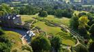 Manor house surrounded by green gardens overlooking valley