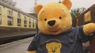 A giant yellow teddy bear on a train platform