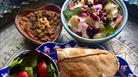 Bowls and plates of colourful Persian food decorated with small flowers