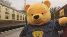 A giant yellow teddy bear on a train platform