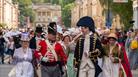 Two men and two women all dressed in Jane Austen-themed costumes leading a procession