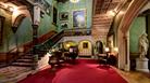 Large grand room with sweeping staircase in an historic house with statue and chandelier