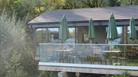 The cafe view from the lake showing tables and chairs and parasols.