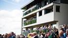 A crowd of spectators watching from the stands at Bath Racecourse