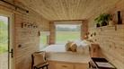 A photo of the cabin interior showing the king-sized bed and full length window overlooking the countryside